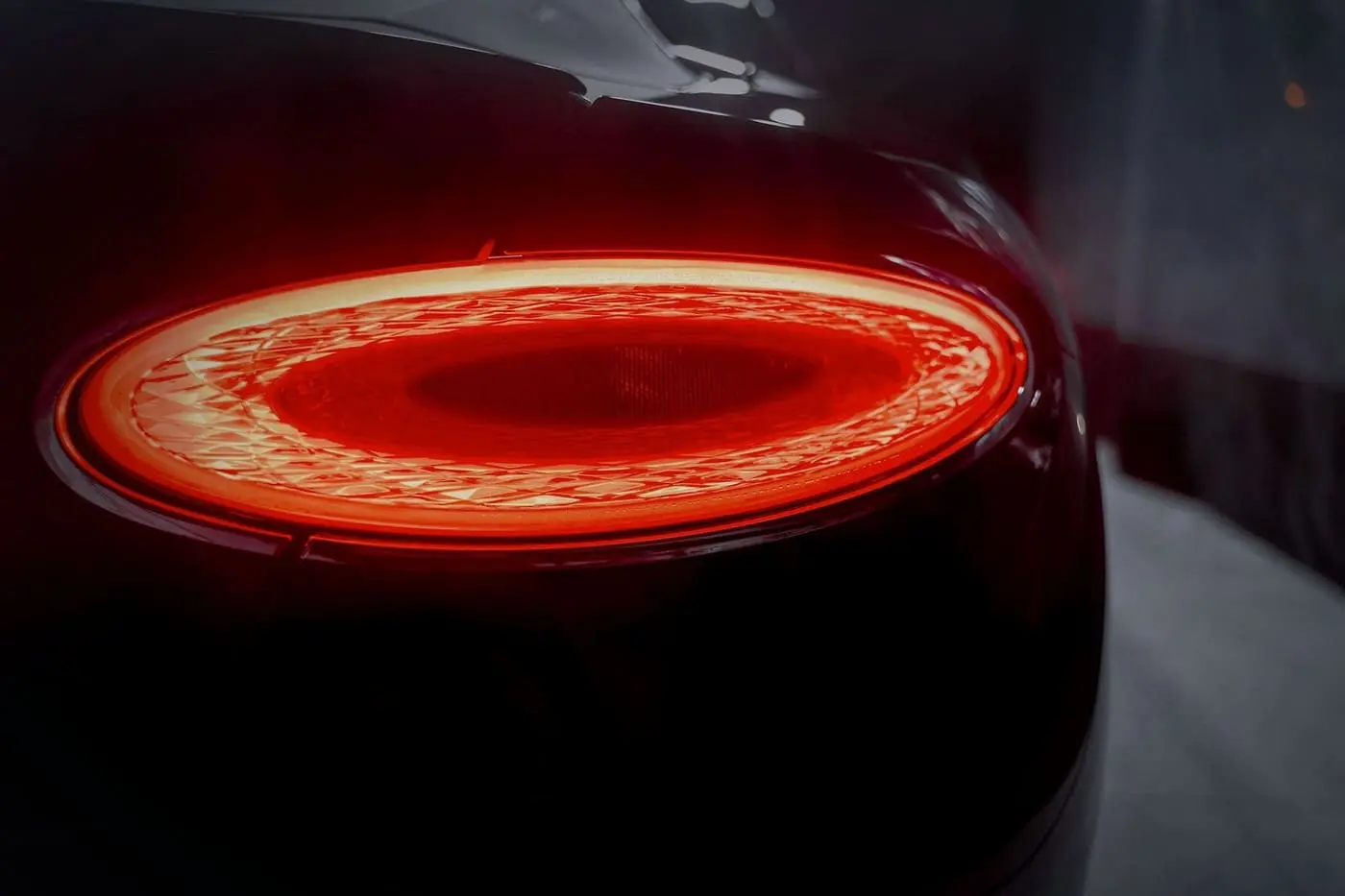 A tail lamp glowing red, close up, on a dark body.