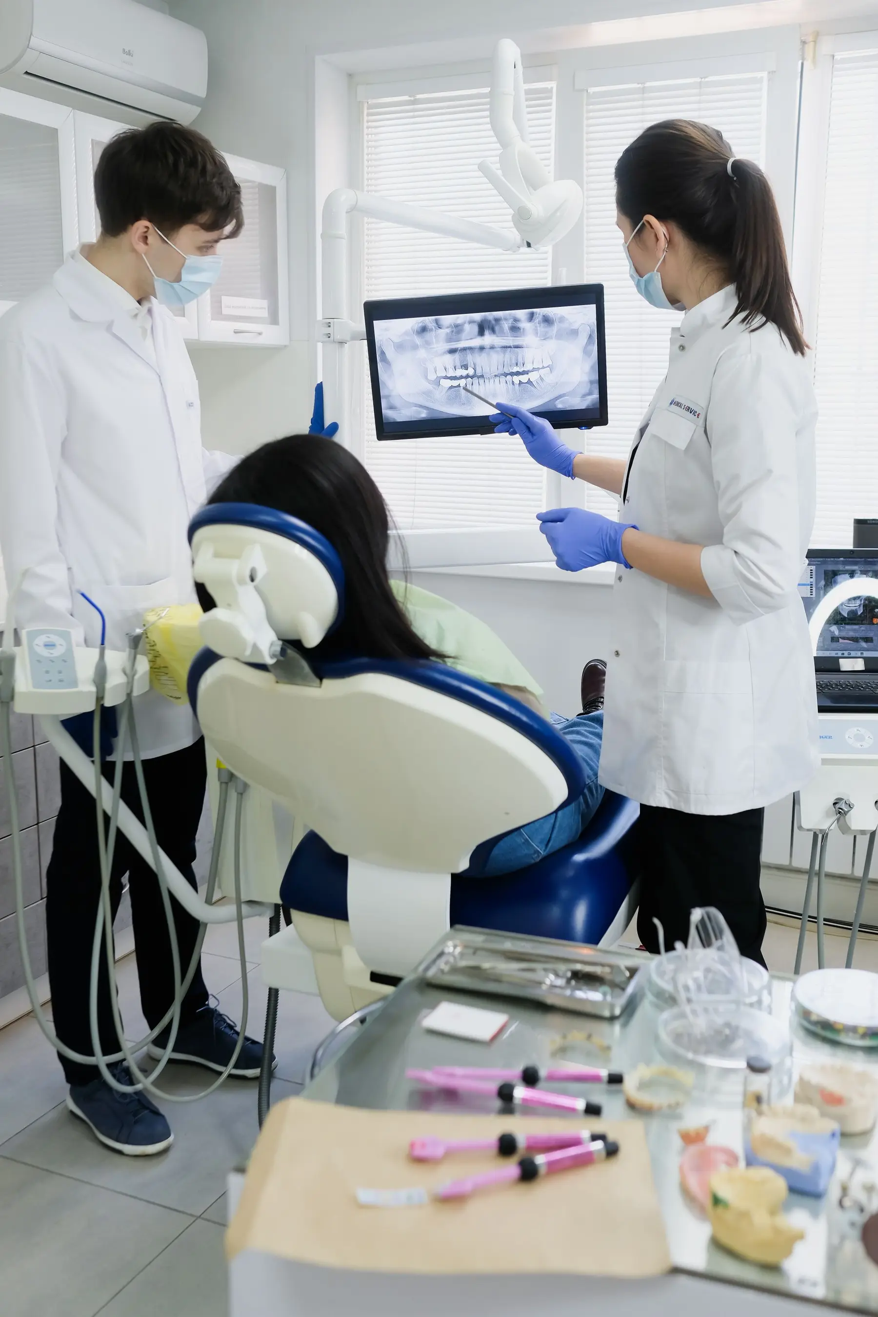 A dental chair in a bright treatment room, with the dentist and assistant at work.