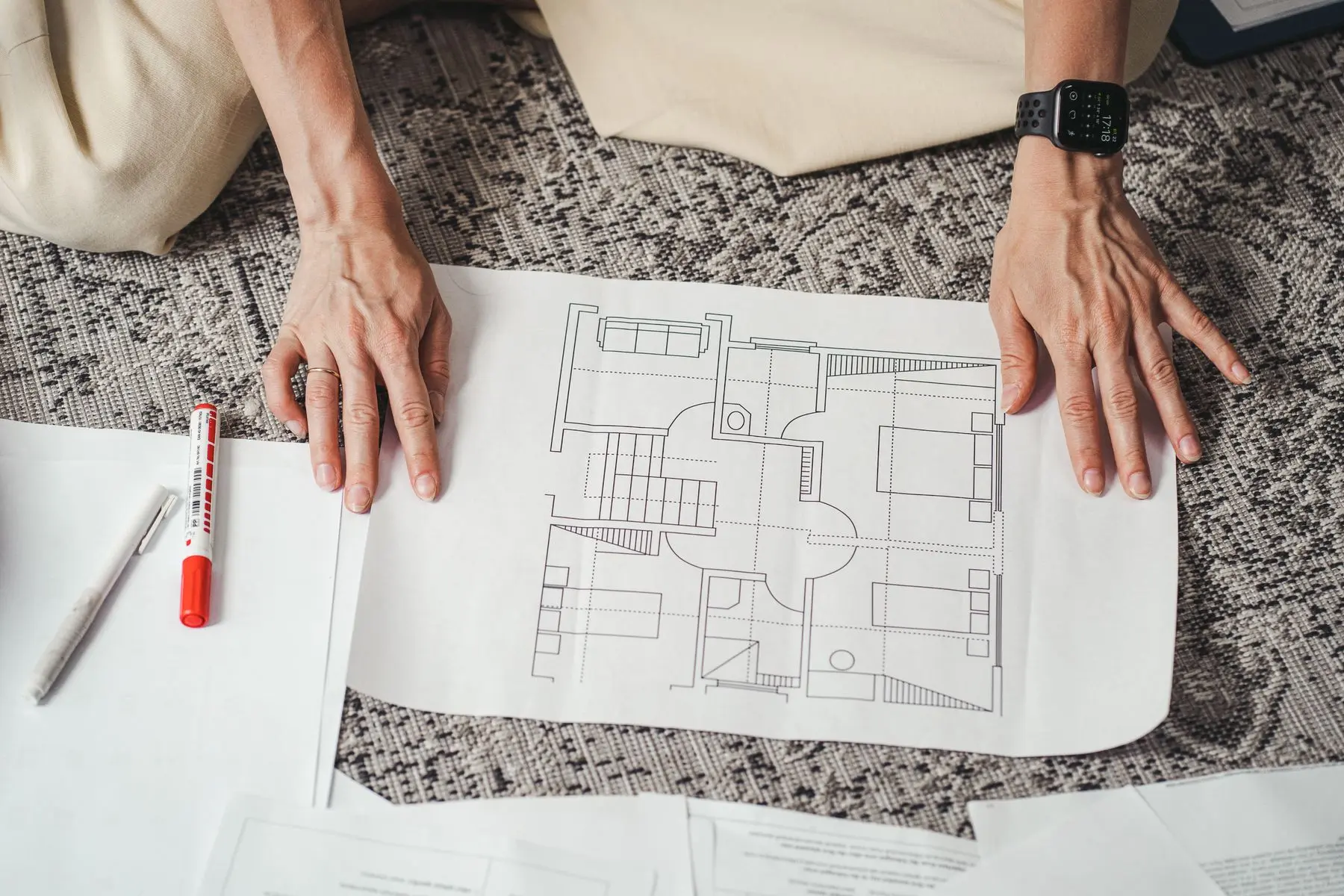 Hands rest on a drawn floor plan of a flat laid on a table.
