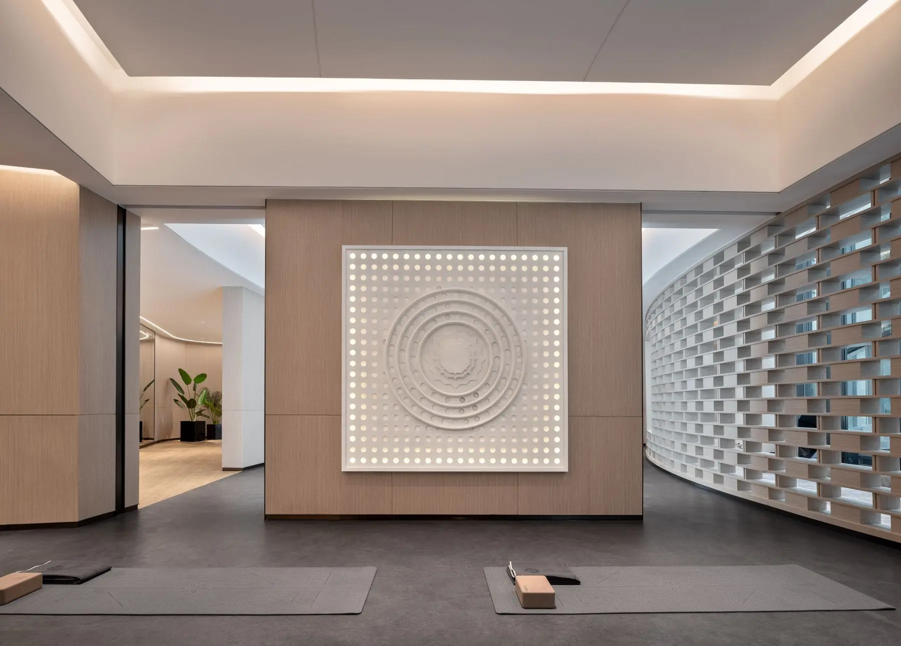 A spacious, minimal studio with a lit circular wall installation and a wooden floor.