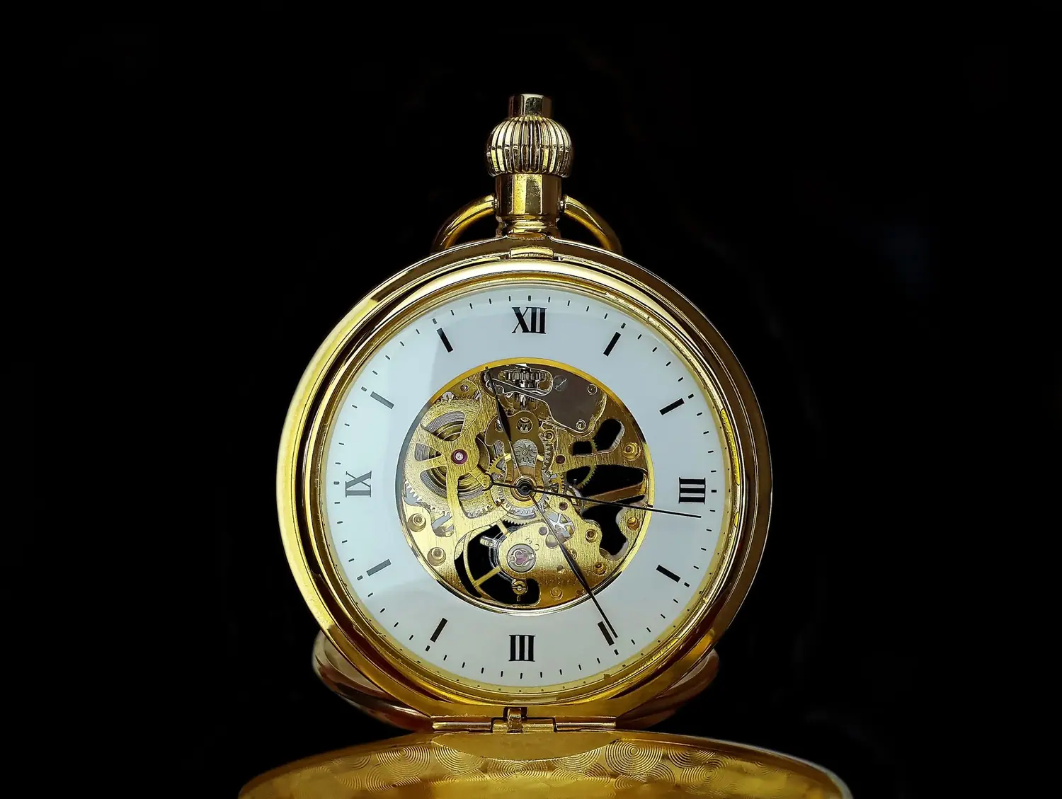 A gold pocket watch with an open skeleton dial on black