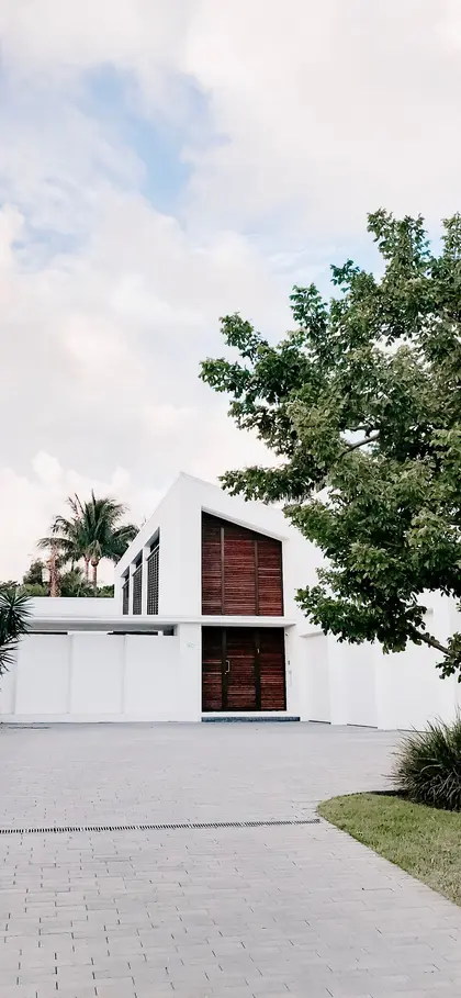 A contemporary white house with a timber-clad gable, seen from the driveway.