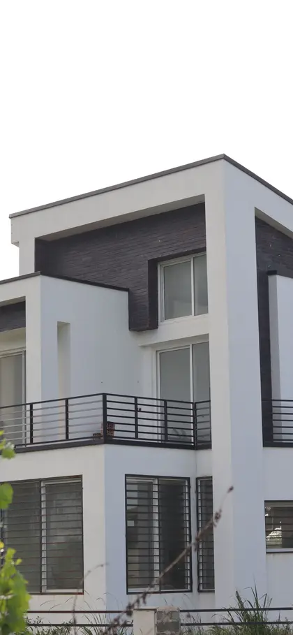 A modern white rendered house with a balcony and large glazed doors.